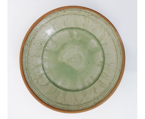 •Richard Batterham, (born 1936) a large stoneware platter, decorated with a band of incised comb decoration under a pale cela