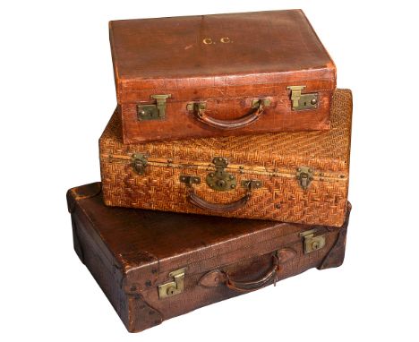Two Edwardian stitched crocodile embossed tan leather suitcases and a Chinese woven rattan suitcasethe smaller stamped in gil