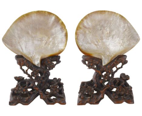 A late 19th century pair of Chinese Canton carved mother of pearl shells on hardwood stands each finely relief carved with fi