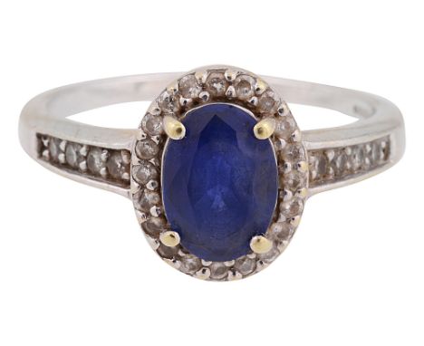 A sapphire and diamond-set cluster ringthe oval mixed-cut sapphire claw-set above the border of brilliant-cut diamonds, taper