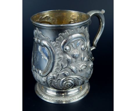 A George II silver baluster shaped mug, embossed with scrolls, flowers and leaves, the cartouche engraved with initials JW, L