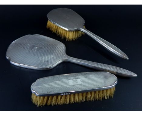 An Art Deco silver mounted three piece dressing table set, with engine turned decoration, Birmingham 1937.