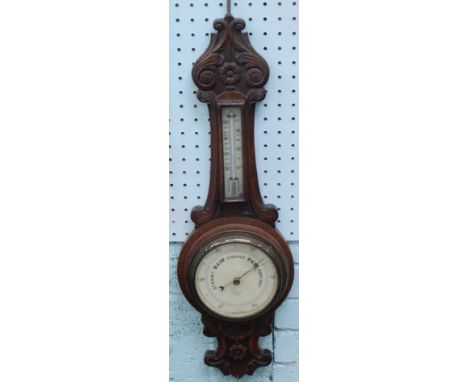 An Edwardian oak cased barometer and thermometer, with 20cm diameter dial and heavily carved onion top case, 79cm high