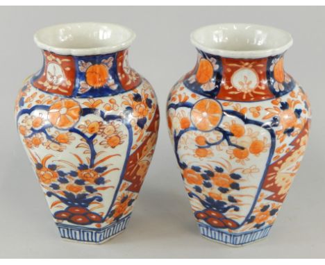 A pair of late Meiji period Japanese Imari pattern vases, each of tapering hexagonal outline, decorated with flowers on plain