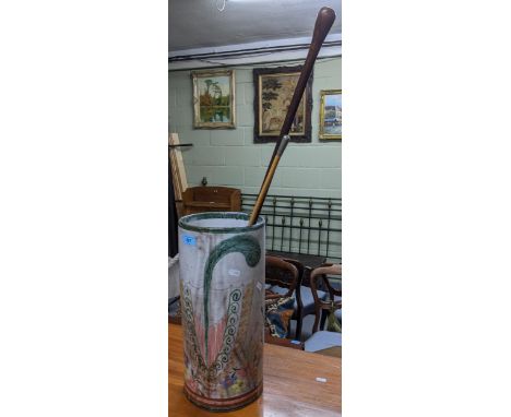 A Portuguese ceramic stick stand decorated with a stylized umbrella flanked by flower heads, containing a swagger stick with 