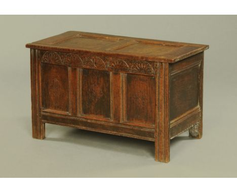 A small 18th century oak three panelled coffer, the top hinging to an interior with left hand compartment with carved frieze 