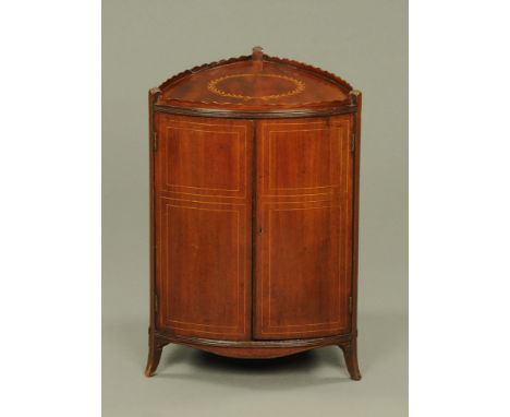 A 19th century inlaid mahogany shield shaped cupboard, with wavy gallery above a pair of panelled doors opening to shelves an