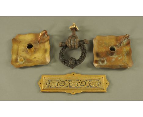 A Victorian cast iron fist door knocker, a brass finger plate and a pair of chamber candlesticks.