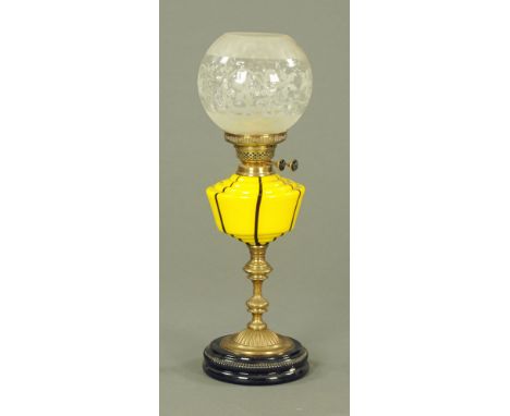 A Victorian brass table oil lamp, with brown striped yellow glass reservoir, knopped stem on black ceramic base, with etched 