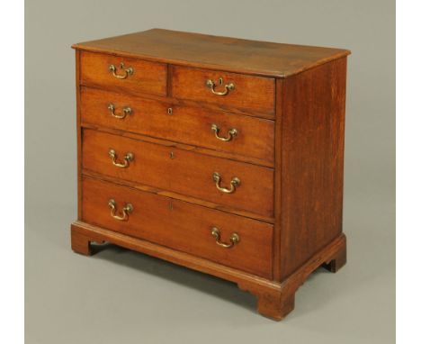 A George III oak chest of drawers, two short and three long with brass drop handles, with circular backplates and brass lock 