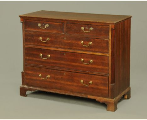 A George III oak chest of drawers, with moulded edge above two short and three long graduated drawers with brass drop handles