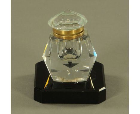 A faceted glass inkwell raised on a black glass plinth.  Width 9.5 cm.