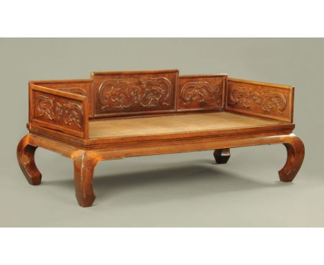 An antique Chinese hardwood daybed, decorated with dragons and with moulded front edge raised on shaped legs.  Height 88 cm, 