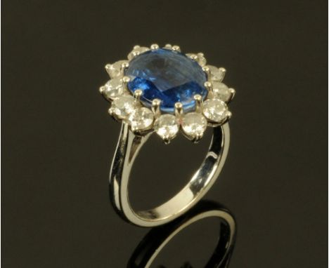 An 18 ct white gold, kyanite and diamond flower head ring, the central oval kyanite +/- 2 carats surrounded by twelve circula