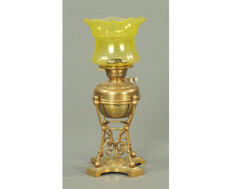 A Victorian brass table oil lamp, of aesthetic design with bulbous reservoir on scrolled rail support and inswept platform ba