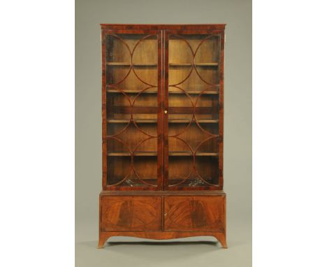 A George III style mahogany bookcase, with moulded cornice above a pair of glazed doors opening to adjustable shelves the bas