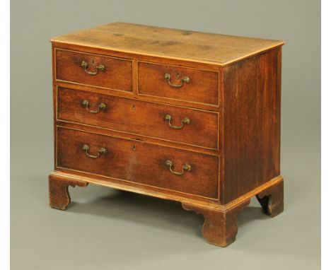 A Georgian oak chest of drawers, two short and two long with brass drop handles and cockbeading to each drawer front and rais