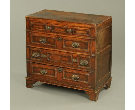 A 17th century oak chest of drawers, four long drawers with cushioned fronts and later brass handles and all raised on later 