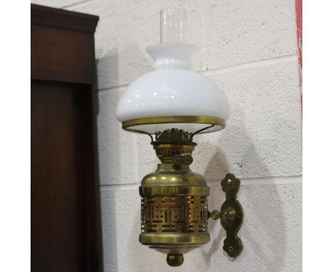 An early 20th century brass wall mounting oil lamp, with white glass shade and chimney, H: 50 cm. Not available for in-house 