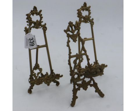 A pair of brass table easels in the rococo style, each H:25cm, and another (3). UK P&amp;P Group 2 (£20+VAT for the first lot