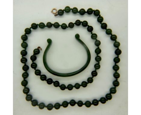 A single strand beaded necklace of polished jade, having a 9ct gold clasp, open L: 64 cm, with a polished jade torq bangle, i