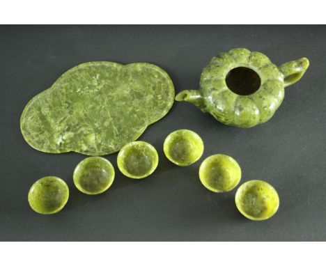 A carved Spinach Jade Chinese tea set. The tea pot (lid missing) of gourd formation with leaf shaped tray and six footed tea 