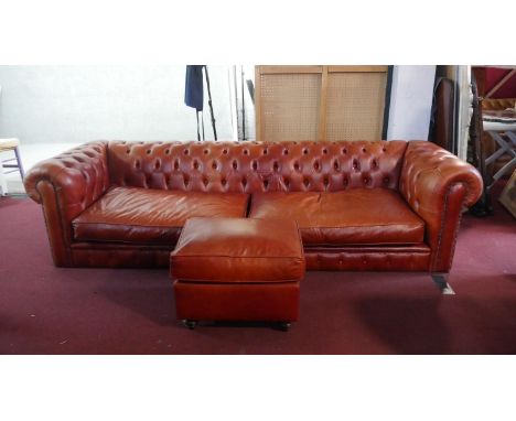 A large red leather Chesterfield sofa, with a button back and scroll arms, together with a leather stool on turned feet. H.65