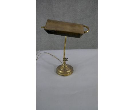 A brass bankers desk lamp, with a curved adjustable stem, on a circular footed base. H.45 W.28cm 