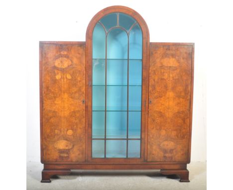 An Art Deco circa 1930's burr walnut display cabinet. Having an arched glazed shelved display cabinet to middle, flanked by t