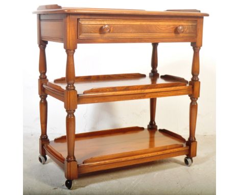 Ercol - A vintage retro mid 20th century elm wood three tier drinks hostess trolley. The trolley having a single drawer with 