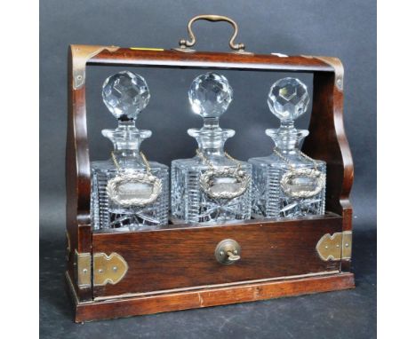 An early 20th century&nbsp;three bottle decanter tantalus with three silver plated spirit labels (Whiskey, Gin &amp; Sherry) 