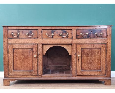 An 18th Century oak Dog Kennel Dresser fitted three drawers above the arched recess flanked by a pair of cupboard doors on br