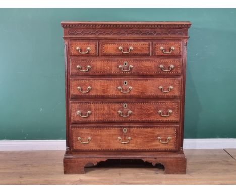 A 19th Century oak and chequer banded Chest with a blind fret carved secret frieze drawer above three small and four long gra