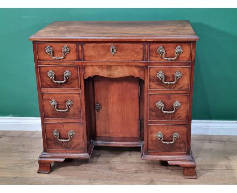 A Georgian mahogany kneehole Desk with moulded top above seven drawers and recessed cupboard raised on ogee bracket supports 