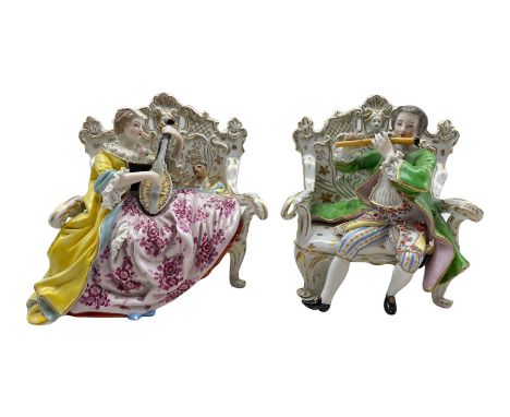 Pair of Hochst porcelain figures modelled as a male and female figure seated on an ornate sofa playing a flute and lute, H12c