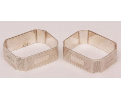 Two George V napkin rings, each of rectangular form with cut corners and all over engine turned decoration and vacant cartouc