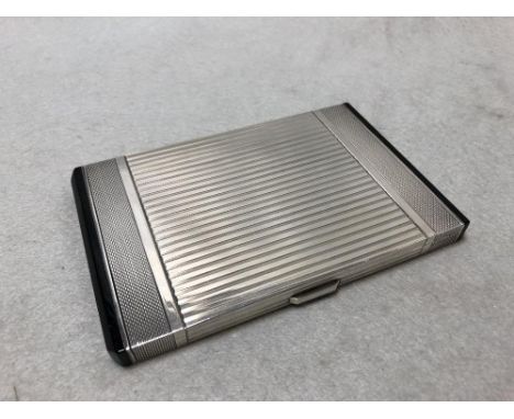 An Art Deco continental metalwares cigarette case, possibly French, the engine turned body with black "onyx" ends, swan mark 