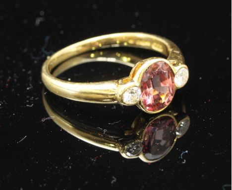 An 18ct gold, ruby of pink sapphire, and diamond ring, centrally set an oval ruby, flanked by two rbc diamonds, estimated 0.2