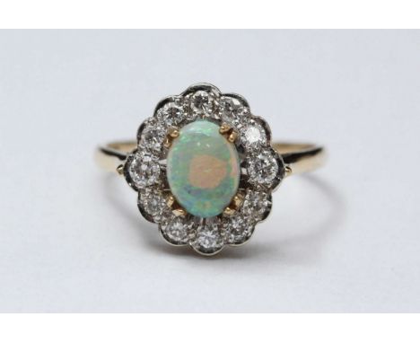 A 9ct gold, opal and diamond ring, centrally claw-set an oval opal measuring 8.20mm x 6.20mm, surrounded by twelve round-face