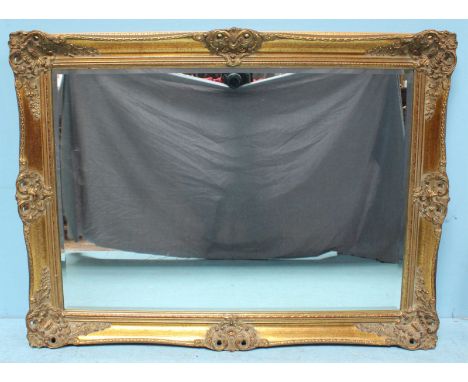 A rectangular bevelled mirror, in ornately carved gilt frame. 77 x 102cm including frame.