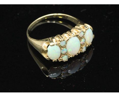 An antique unmarked gold and opal ring, set with three large oval opals interspersed with six small round opals, 4.87g