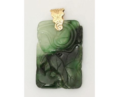 An carved jade pendant, ornately decorated with scrolls and flowers, mounted on a carved yellow metal suspension loop. 21g.