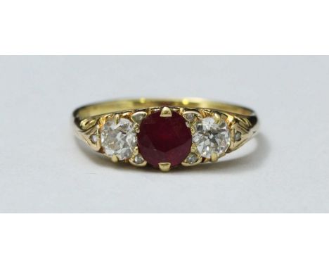 An 18ct gold ruby and diamond ring, with scroll-carved head centrally set with an oval faceted ruby, 6.00mm, flanked by two V