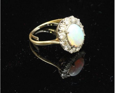 An unmarked gold, opal and diamond ring, centrally claw-set a large oval opal measuring 10.76mm x 8.31mm, surrounded by twelv