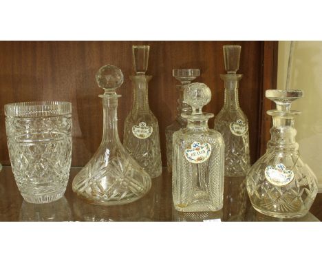 Six assorted cut glass decanters, five with ceramic spirit labels and a cut glass vase.