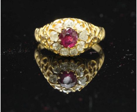 A late 19th/early 20th century 15ct gold ring, of pierced scrollwork design, centrally set with a round faceted ruby measurin