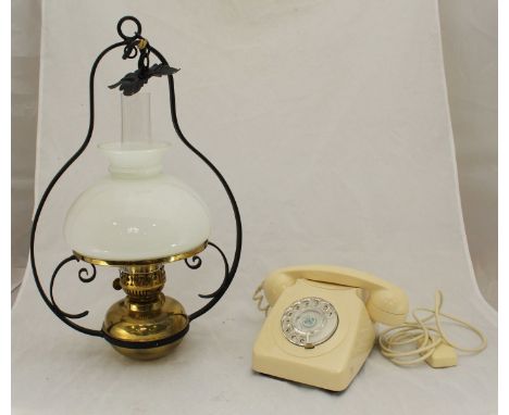 A brass hanging oil lamp and a vintage cream, Bakelite telephone.