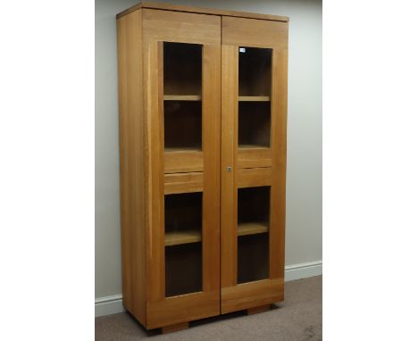 Light oak bookcase enclosed by two glazed doors, W101cm, H196cm, D46cm   Condition Report   Click here for further images, co