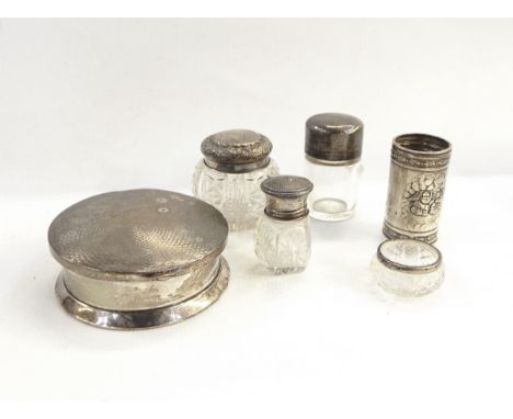 Silver dressing table box of circular form with hinged engine-turned cover, four glass dressing table jars with silver mounts