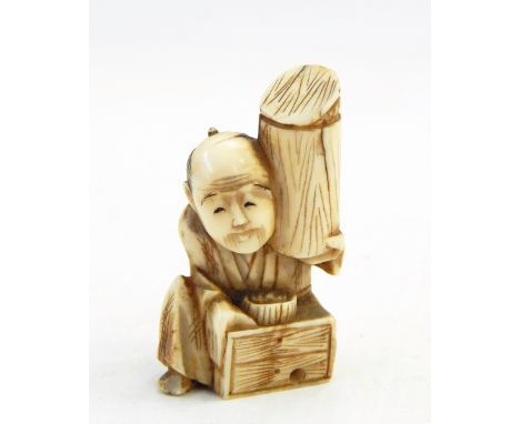 Japanese carved ivory netsuke, man seated and holding a cylinder, 4cm high 